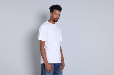 Açık gri arka planda beyaz tişört giyen bir adam. Tasarım için model