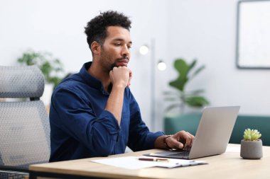 ofiste masada dizüstü bilgisayarda çalışan adam