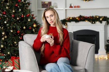 Güzel bir kadın krem şantili, tarçınlı ve portakal dilimli sıcak kakao içiyor. Noel sezonu