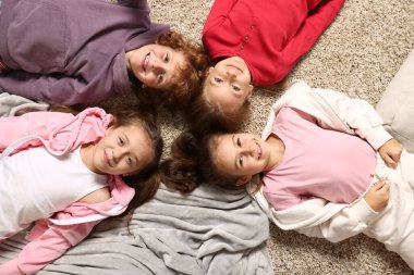 Pijamalı şirin çocuklar evde yerde yatıyor, manzaranın üstünde.