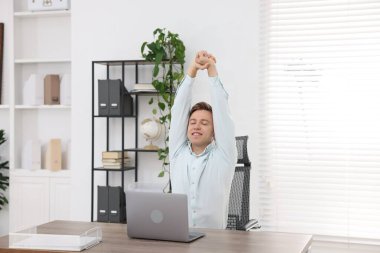 Genç işadamı kollarını uzatıp, masada oturuyor.