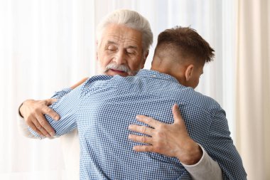 Baba ve oğul evde birbirlerine sarılıyorlar.