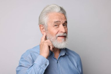 Açık gri arka planda işitme cihazı olan son sınıf öğrencisi.