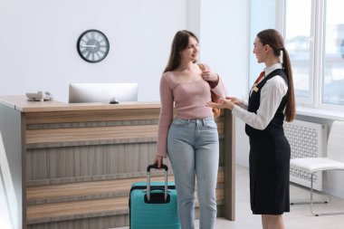 Üniformalı resepsiyonist misafirleri içeri buyur ediyor, mesaj için yer var.