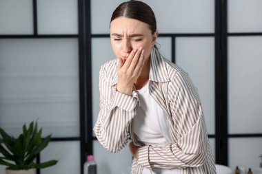 Banyoda mide ağrısı ve bulantısı olan bir kadın. Mesaj atmak için yer var.