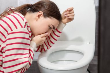 Tuvaletteki klozet yüzünden midesi bulanan kadın.