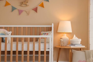 Beşik, masa, lamba ve dekorlu şık bir bebek odası. İç tasarım