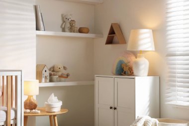 Beşiği, lambası, oyuncakları ve şifoniyeri olan şık bir bebek odası. İç tasarım