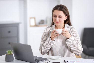 Ofisteki beyaz masada kahve molası veren kadın.