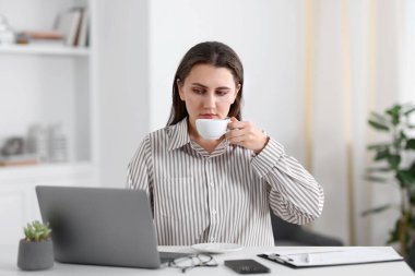 Ofisteki beyaz masada kahve molası veren kadın.