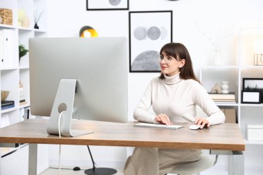 Ofisteki bilgisayarda çalışan genç bir kadın.