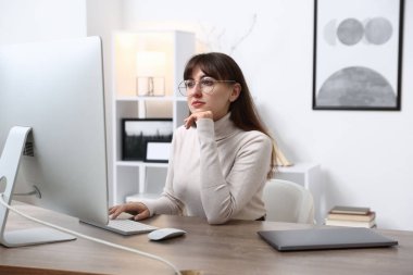 Ofisteki bilgisayarda çalışan genç bir kadın.