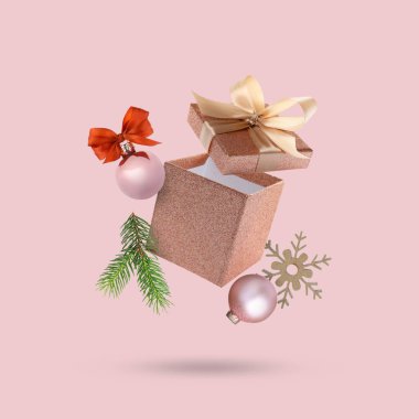 Noel ya da yeni yıl kutlaması. Pembe arka planda uçan hediye kutusu ve şenlikli dekor.