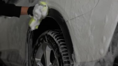 Oto yıkayan adam araba yıkamada süngerle yıkıyor.