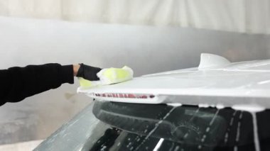 Oto yıkayan adam araba yıkamada süngerle yıkıyor.