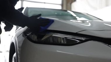 Adam oto yıkamada bez ile araba siliyor, yakın plan.