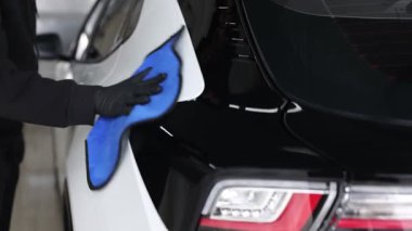 Adam oto yıkamada bez ile araba siliyor, yakın plan.