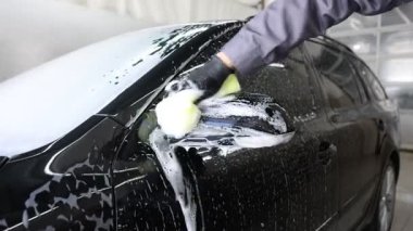 Oto yıkayan adam araba yıkamada süngerle yıkıyor.