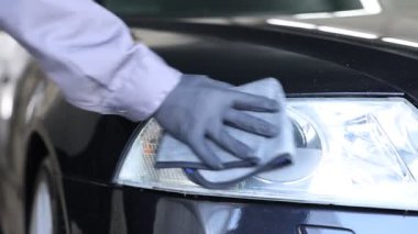 Adam oto yıkamada bez ile araba siliyor, yakın plan.