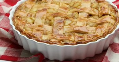 Lezzetli ev yapımı elmalı turta fırın kabında beyaz ahşap masada dönüyor, yakın plan.