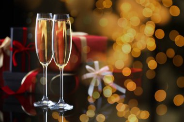 Bardaklarda köpüklü şarap, hediye kutuları, lambalar. Yeni yıl tebrik kartı.