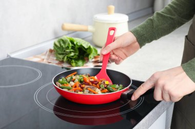 Kızartma tavasında taze sebze ve spatula karıştıran kadın, yakın plan.