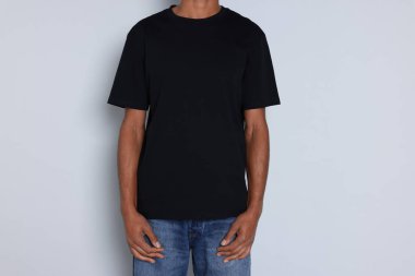 Açık gri arka planda siyah tişört giyen adam, yakın plan. Tasarım için model