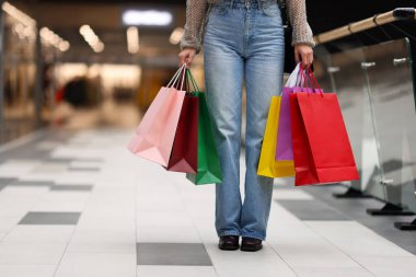 Alışveriş merkezinde farklı alışveriş torbaları olan bir kadın, yakın plan. Metin için boşluk