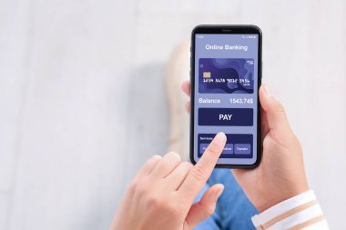 Çevrimiçi ödeme. Bankacılık uygulamasını kapalı mekanda akıllı telefonda kullanan bir kadın.