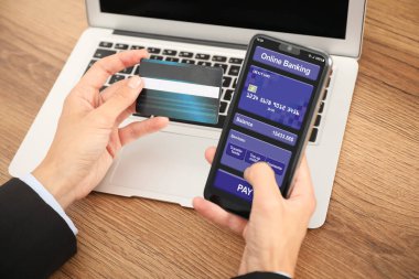 Kredi kartı olan bir adam online ödeme için akıllı telefonu kullanıyor, yakın plan.