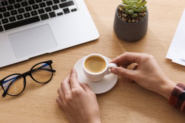 Ahşap masada kahve molası veren bir kadın, yakın plan.
