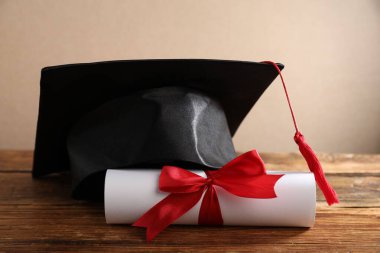Mezuniyet şapkası ve diploması ahşap masada, yakın plan.