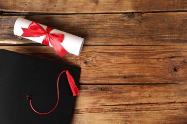 Mezuniyet şapkası ve diploması tahta masada, düz yatıyordu. Metin için boşluk