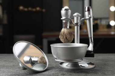 Berber dükkanındaki gri desenli masada berber aletleri ve ayna olan metal standı, yakın plan.