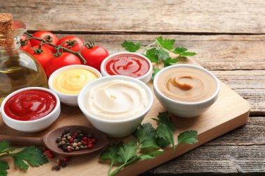 Tabaklardaki farklı soslar ve ahşap masadaki malzemeler, yakın plan.