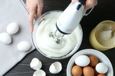 Siyah ahşap masada yumurta beyazı çırpan bir kadın.