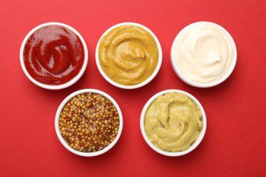 Kırmızı arka planda farklı soslar, düz yatış.