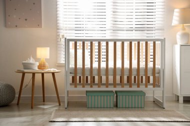 Beşik, masa, lamba ve dekorlu şık bir bebek odası. İç tasarım