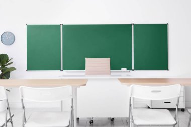 Sınıfta yeşil karatahta, masalar ve sandalyeler var. Tasarım için model