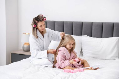 Evde saç bigudili bir anne, kızının saçını evde yapıyor. Metin için boşluk