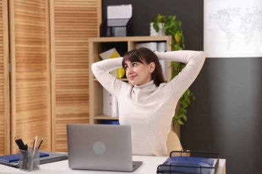 Genç iş kadını ofiste sırtını esnetiyor.