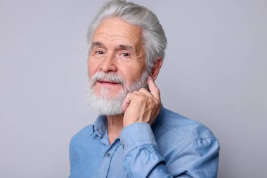 Açık gri arka planda işitme cihazı olan son sınıf öğrencisi.