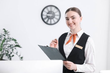 Kapalı resepsiyonda not panosu ve kalemi olan mutlu bir resepsiyonist.