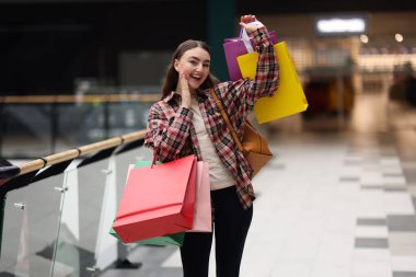 Alışveriş merkezinde farklı çantaları olan bir kadın.