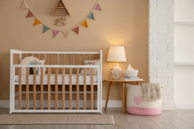 Beşik, masa, lamba ve dekorlu şık bir bebek odası. İç tasarım