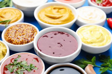 Mavi arka planda farklı soslar ve otlar, yakın plan.