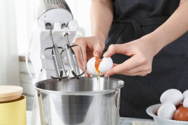 Mutfaktaki masada yumurta kıran kadın, yakın plan.