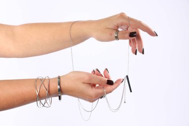 Beyaz arka planda şık gümüş aksesuarlar giyen genç kadın, yakın plan.