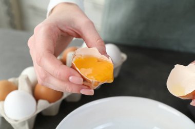 Mutfaktaki gri masada yumurta kıran kadın, yakın plan.