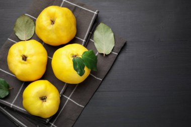 Olgun ayva ve yeşil yapraklar, siyah ahşap masa, üst manzara. Metin için boşluk